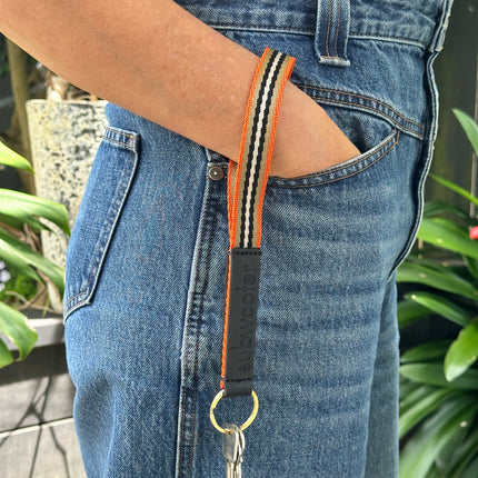 subwooferdog-orange-sand-keyring-on-wrist-in-front-pocket